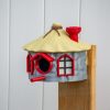 Bunt bemaltes Vogelhaus mit rundem Strohdach und roten Fensterrahmen, PrintHero